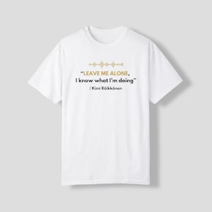 May include: A white short-sleeved t-shirt featuring a gold sound wave graphic above the text "LEAVE ME ALONE, I know what I'm doing" in black and gold lettering, followed by the name "Kimi Räikkönen" printed in black on the chest area.