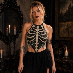 May include: A dark green crochet halter top featuring a cream-colored rib cage and spine design on the front. The garment has a pointed hemline with intricate spiderweb detailing along the lower edges, crafted from yarn in a sleeveless style.