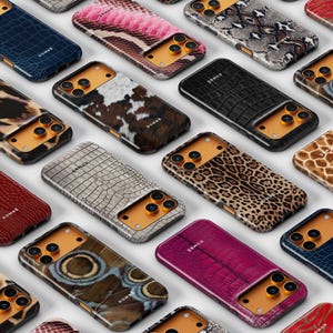 May include: A collection of smartphone cases featuring diverse textures and patterns, including animal prints, reptile skin, and stone motifs. Each case has a gold-toned camera cutout area and the brand name DOMBE printed on the back surface.