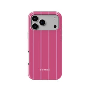 Puede incluir: Una funda para smartphone de color rosa intenso con rayas verticales de color rosa claro y un área rectangular gris claro para la cámara. La palabra DOMBE está impresa en blanco cerca del centro inferior de la funda. Tiene un acabado liso.