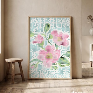 Puede incluir: Una obra de arte rectangular en punto de cruz con un patrón floral de flores rosas, hojas verdes y un fondo azul claro. El diseño está compuesto por pequeñas puntadas en forma de X, presentado en un marco de madera clara.
