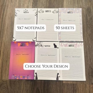 May include: Six 5x7 inch notepads with 50 sheets each, featuring various Halloween-themed designs including bats, pumpkins, cats, and ghosts. Each notepad has the word NOTES at the top, horizontal lines for writing, and the text This is Halloween.