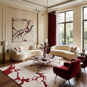 Puede incluir: Una sala de estar con dos sof&aacute;s curvos color crema, dos sillones rojo oscuro y una mesa de centro cuadrada de m&aacute;rmol. Una alfombra grande con un patr&oacute;n abstracto rojo cubre el suelo. Una l&aacute;mpara de ara&ntilde;a dorada cuelga arriba y un gran cuadro abstracto decora la pared.
