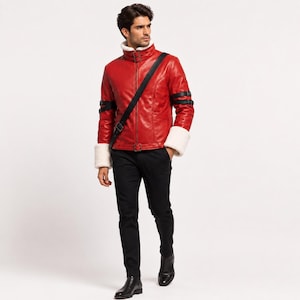 Peut inclure: Une veste en cuir rouge vif dotée d'un col montant avec deux sangles à boucle, de poignets en fausse fourrure blanche et de sangles noires à boucle sur chaque bras. La veste comprend une bandoulière noire, un pantalon noir et des bottes noires.