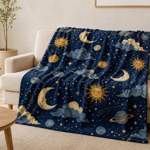 以下が含まれることがあります： 顔が描かれた金色の太陽、三日月、輪のある惑星、散りばめられた星々が描かれた紺色のスローケット。生地の表面全体に、柔らかくぼやけた青い雲が点在する天体模様がデザインされています。