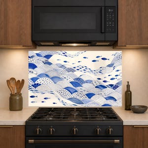 May include: A rectangular kitchen backsplash panel featuring a blue and white pattern of stylized waves and small fish. The design consists of overlapping semi-circular shapes filled with intricate floral, dotted, and linear motifs on a cream background.