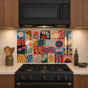 May include: A rectangular kitchen splashback panel featuring a grid of colourful squares with various botanical and abstract patterns including flowers, leaves, waves, and arches in shades of red, blue, yellow, pink, and green, positioned behind a black stove.