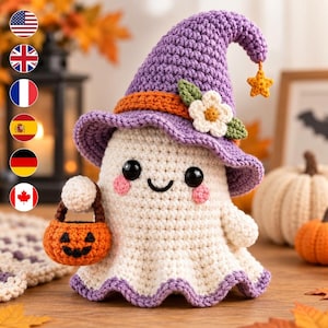Op de afbeelding: Een gehaakt spookfiguurtje met een paarse puntmuts voorzien van een oranje band, een witte bloem en een klein geel sterretje aan de punt. Het spookje heeft zwarte ogen, roze wangen en een glimlach, en houdt een klein oranje pompoenemmertje vast.