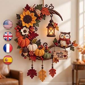 May include: A crescent-shaped autumn wreath made of crocheted elements including a large sunflower, pumpkins, acorns, and leaves. A crocheted owl sits on the right, next to a hanging lantern and a sign that reads Hello Fall with a heart.