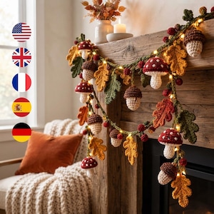 May include: A decorative garland featuring crocheted elements including red and white mushrooms, brown and cream acorns, and green and orange oak leaves, interspersed with small warm white fairy lights along a green yarn strand.