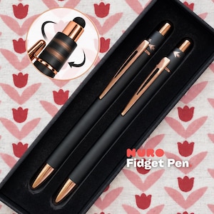 Könnte beinhalten: Zwei mattschwarze Nuro Fidget-Stifte mit roségoldenen Akzenten, einschließlich Clips und Spitzen, präsentiert in einer schwarzen Box. Ein eingefügter Kreis zeigt eine Nahaufnahme der Stiftkappe mit einem rotierenden Fidget-Mechanismus und einer schwarzen Stylus-Spitze.