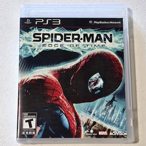 May include: A PlayStation 3 video game case for Spider-Man: Edge of Time. The cover features a red and blue Spider-Man mask with a futuristic city skyline in the background, the ESRB Teen rating symbol, and the Beenox, Marvel, and Activision logos.
