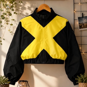 May include: A black and yellow cropped jacket featuring a high collar, a full-length front zipper, and long sleeves with elastic cuffs. The design includes a large, bold yellow X-shaped pattern across the chest and back on a black base.