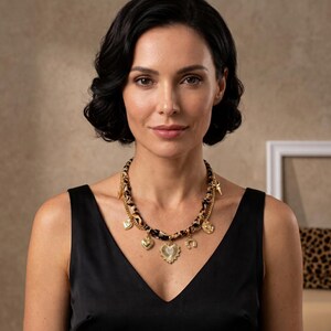 May include: A gold-toned necklace featuring a thick, leopard-print fabric cord layered with a delicate gold chain. The necklace is adorned with multiple gold-toned charms, including a central heart pendant, a horseshoe, and small circular discs.