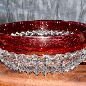 May include: A red glass bowl with a clear, diamond-shaped patterned base. The bowl has a deep red color and a shiny finish.