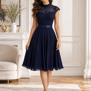 May include: A navy blue knee-length dress featuring a high-neck lace bodice with short cap sleeves and a solid satin waistband. The skirt is made of a flowing, pleated chiffon fabric that falls from the waist, creating a soft, flared silhouette.