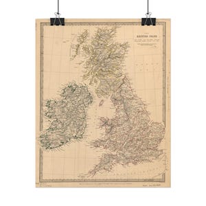May include: A vintage-style map titled The British Isles, printed on aged beige paper with black ink. The map displays detailed topography, coastlines, and regional labels for Great Britain and Ireland, suspended by black metal clips at the top.