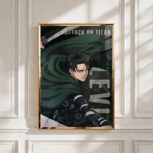 Op de afbeelding: Een ingelijste poster met een anime-personage met zwart haar, gekleed in een donkergroene cape en zwarte tactische uitrusting. De tekst ATTACK ON TITAN en LEVI is zichtbaar op de achtergrond. Het personage heeft een serieuze uitdrukking en is afgebeeld in een dynamische houding met een gedeeltelijk zichtbaar zwaardblad.