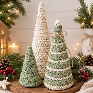 May include: Three cone-shaped decorative trees made of crocheted yarn. One tall tree is solid cream, one medium tree features alternating horizontal stripes of sage green and cream with a jute twine bow, and one small tree is solid sage green.