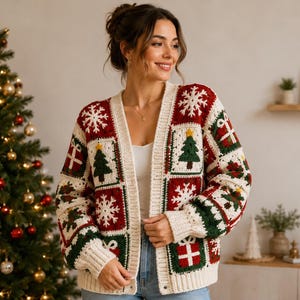 Op de afbeelding: Een gehaakt vest met een patchworkontwerp van rode, groene en crèmekleurige vierkanten. De vierkanten tonen kerstmotieven zoals witte sneeuwvlokken, groene kerstbomen met gele sterren en rode cadeautjes met witte linten.