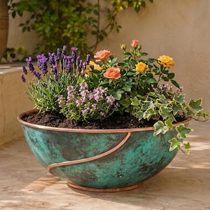 Puede incluir: Una maceta ancha en forma de cuenco con un acabado de pátina desgastada en tonos turquesa y cobre, que presenta una banda lisa de color cobre alrededor del exterior. La maceta está llena de tierra oscura, lavanda morada, rosas rosas y amarillas, e hiedra.