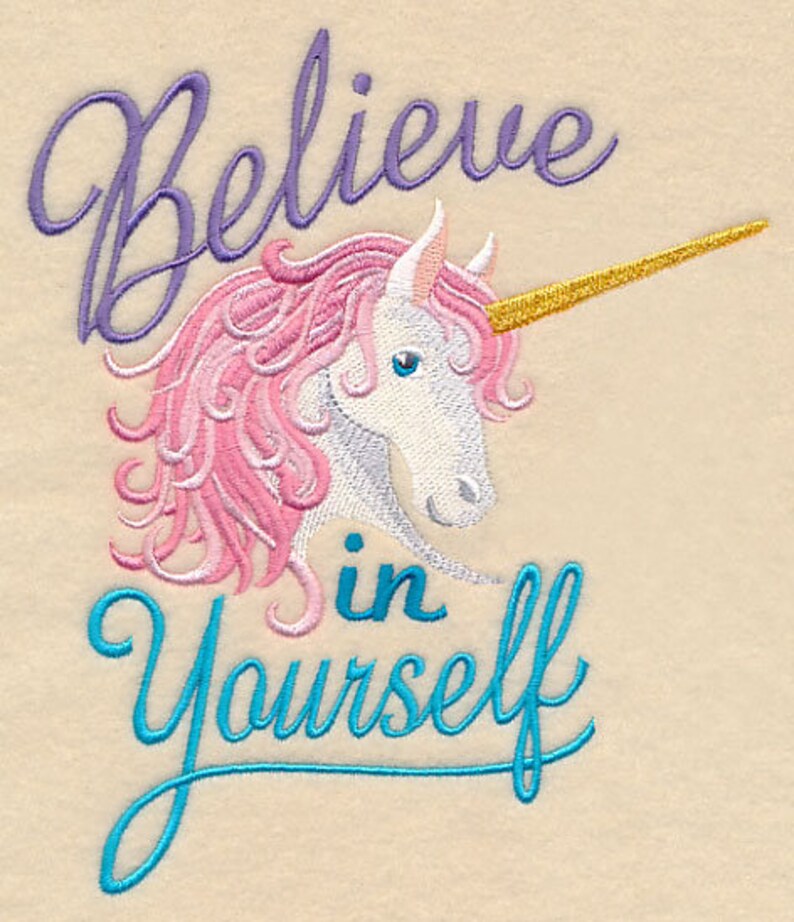 May include: Embroidered design featuring a unicorn with pink mane and a golden horn. The text "Believe in Yourself" is written above and below the unicorn in purple and teal script, respectively. The background is a light beige color.