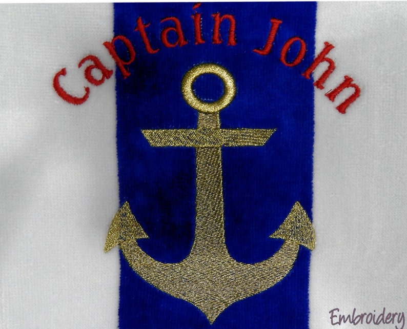 Puede incluir: Toalla blanca con una franja azul con un dise&ntilde;o de ancla dorada. Las palabras "Captain John" est&aacute;n bordadas en rojo encima del ancla. El dise&ntilde;o est&aacute; centrado en la toalla.