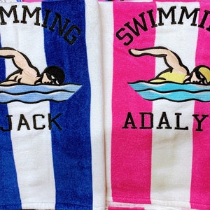 May include: Two striped beach towels, one blue and white, the other pink and white. Each towel features an embroidered swimmer graphic and the name "Jack" or "Adalyn" in black lettering, with the word "SWIMMING" above.