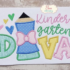 May include: Embroidered design featuring a pencil, hearts, and the words "Kindergarten Diva." The pencil is blue with a pink bow. The letters are green, yellow, and pink. The design is on a white background.