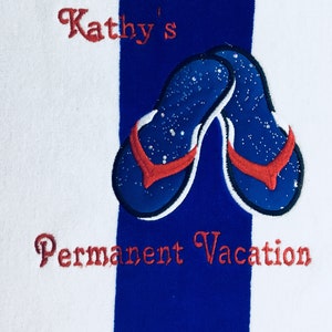 May include: White and blue striped beach towel with embroidered blue flip-flops with red straps. The towel has the text "Kathy's" and "Permanent Vacation" embroidered in red.