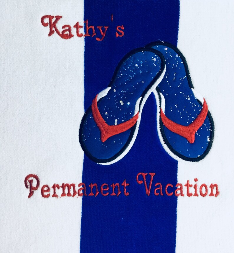 May include: White and blue striped beach towel with embroidered blue flip-flops with red straps. The towel has the text "Kathy's" and "Permanent Vacation" embroidered in red.