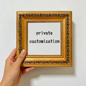 Puede incluir: Un marco de fotos cuadrado con un acabado dorado metálico ornamentado y un borde decorativo en relieve. El centro del marco contiene una inserción blanca con el texto negro "private customization" impreso en una fuente sencilla sin remates.