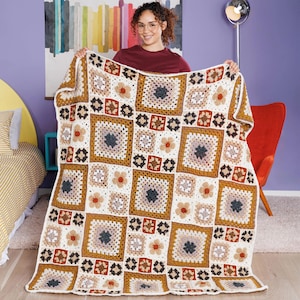 May include: A handmade crochet blanket featuring a repeating pattern of large and small squares in shades of cream, mustard yellow, dark brown, and muted gray. The design consists of intricate granny square motifs joined together in a grid.