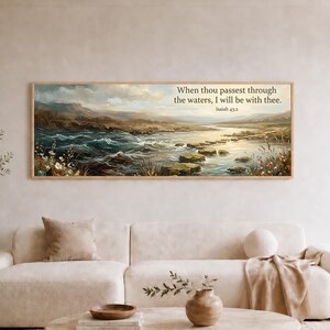 May include: A rectangular landscape wall art print featuring a river with stepping stones, rolling hills, and wildflowers. The text "When thou passest through the waters, I will be with thee. Isaiah 43:2" is printed in the upper right corner.
