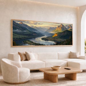 Può includere: Un dipinto paesaggistico panoramico in una cornice di legno chiaro che raffigura un fiume tortuoso che scorre attraverso una valle circondata da imponenti montagne innevate sotto un cielo dorato con nuvole sparse e pendii verdeggianti.