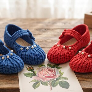 May include: Two pairs of handmade crochet shoes, one pair in blue and one pair in red. Each shoe features a rounded toe, a single strap across the top with a crocheted flower accent, and a row of small white faux pearls along the front edge.