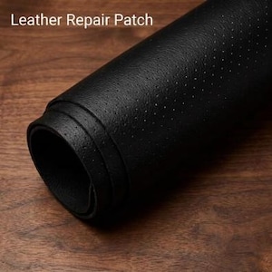 May include: A rolled black leather repair patch featuring a perforated texture across its surface. The text Leather Repair Patch is visible in the upper left corner of the image, indicating the function of this black material roll.