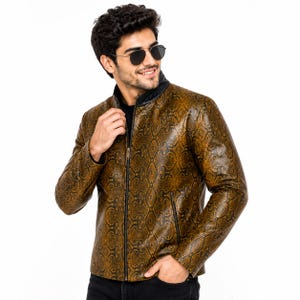 Può includere: Una giacca a maniche lunghe con motivo a pelle di serpente marrone e nero, colletto alla coreana nero e chiusura centrale con zip nera. La giacca presenta due tasche laterali con zip nere ed è indossata con pantaloni di colore scuro.