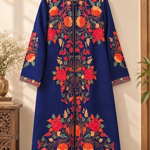 May include: A long-sleeved navy blue coat featuring a mandarin collar and a front button closure. The garment is decorated with vibrant floral embroidery in shades of red, orange, and yellow, extending across the chest, sleeves, and hem.