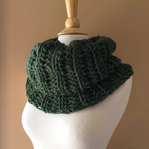 Peut inclure: Un col roulé en crochet vert sur un mannequin blanc.