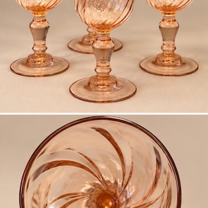 May include: A set of four pink glass goblets featuring a swirling ribbed pattern on the bowl and a pedestal base. The top view shows the spiral design radiating from the center of the glass, while the side view displays the stem and foot.