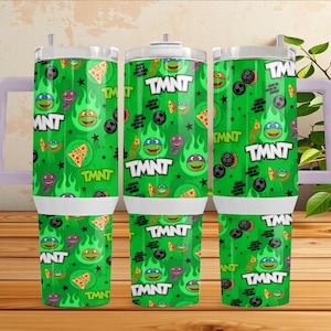 Puede incluir: Un vaso de acero inoxidable verde con asa, que presenta un patrón repetitivo de caras de las Tortugas Ninja, porciones de pizza, estrellas negras e iconos de ladrillos. El texto TMNT está impreso en letras blancas sobre la superficie.