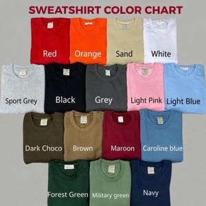 May include: A sweatshirt color chart displaying seventeen folded crewneck sweatshirts in various colors including red, orange, sand, white, sport grey, black, grey, light pink, light blue, dark choco, brown, maroon, caroline blue, forest green, military green, and navy.