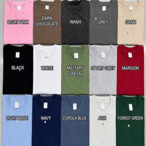 May include: A T-shirt color chart displaying fifteen folded shirts in various colors including light pink, dark chocolate, wash, grey, sand, black, white, military green, sport grey, maroon, light blue, navy, corola blue, ash, and forest green.