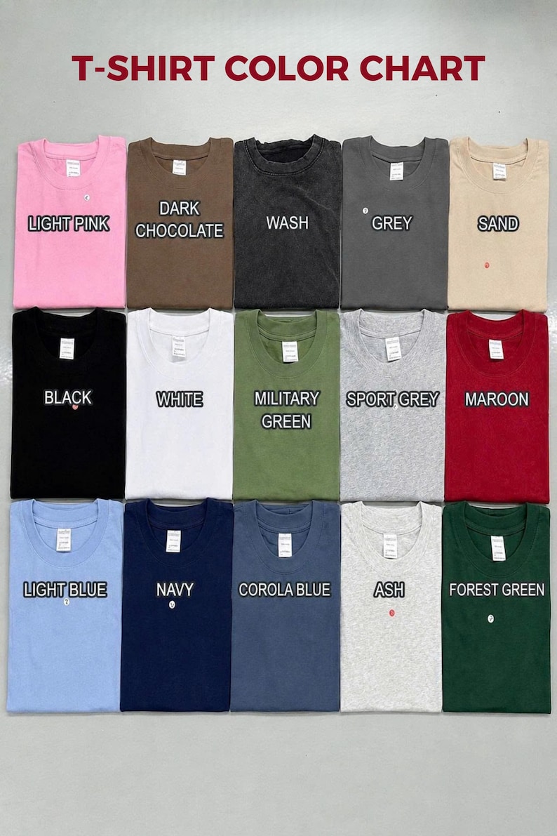 May include: A T-shirt color chart displaying fifteen folded shirts in various colors including light pink, dark chocolate, wash, grey, sand, black, white, military green, sport grey, maroon, light blue, navy, corola blue, ash, and forest green.