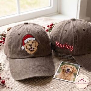 Könnte beinhalten: Zwei braune Baseballkappen mit Stickereien. Eine Kappe zeigt einen Golden Retriever mit einer rot-weißen Weihnachtsmütze. Die andere Kappe trägt den Namen Marley, gestickt in rot-weiß gestreiften Buchstaben im Zuckerstangen-Design.