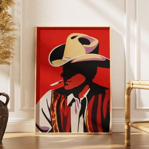 May include: A rectangular wall art print featuring a stylized graphic illustration of a cowboy wearing a wide-brimmed hat and a patterned vest. The figure is shown in profile against a solid red background, with a cigarette held in the mouth.