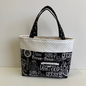May include: Black and white tote bag with a white background and black lettering. The lettering includes the words "Lord's", "Prince of Peace", "Messiah", "Lamb of God", and "Jesus".