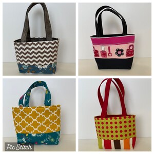 Könnte beinhalten: Vier verschiedene Tragetaschen mit verschiedenen Mustern und Farben. Die Taschen sind aus Stoff und haben einen Reißverschluss. Die Taschen sind alle klein und eignen sich perfekt zum Tragen kleiner Gegenstände.