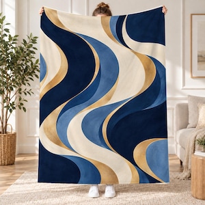 May include: A rectangular throw blanket featuring a repeating pattern of flowing, curved waves in shades of deep navy blue, light blue, cream, and metallic gold. The design consists of smooth, sweeping lines that create a sense of movement.